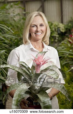 Stock Photo - Portrait of a happy senior blond woman in botanical garden. Fotosearch