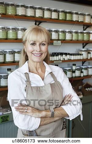Stock Image - Portrait of a happy senior employee with arms crossed in spice store. Fotosearch