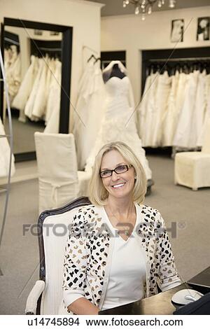 Portrait of a happy senior female wearing eyeglasses sitting in bridal store View Large Photo Image Picture - Portrait of a happy senior female wearing eyeglasses sitting in bridal store. Fotosearch