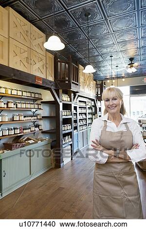 Portrait of a happy senior female spice merchant standing with arms crossed in store View Large Photo Image Stock Image - Portrait of a happy senior female spice merchant standing with arms crossed in store. Fotosearch