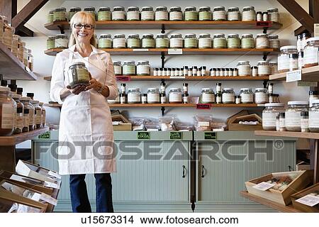 Portrait of a happy senior merchant standing with spice jar in store View Large Photo Image Picture - Portrait of a happy senior merchant standing with spice jar in store. Fotosearch