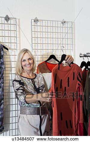 Portrait of a happy senior woman browsing in fashion boutique View Large Photo Image Stock Photo - Portrait of a happy senior woman browsing in fashion boutique. Fotosearch