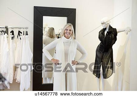 Stock Photo - Portrait of a happy senior woman trying on clothes in fashion boutique. Fotosearch