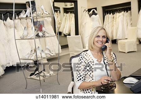 Portrait of a happy woman making a call in bridal store View Large Photo Image Stock Image - Portrait of a happy woman making a call in bridal store. Fotosearch