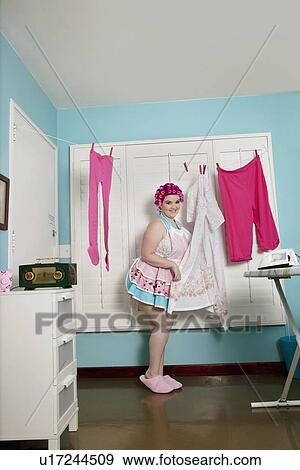Stock Photo - Portrait of a happy woman standing near clothesline. Fotosearch