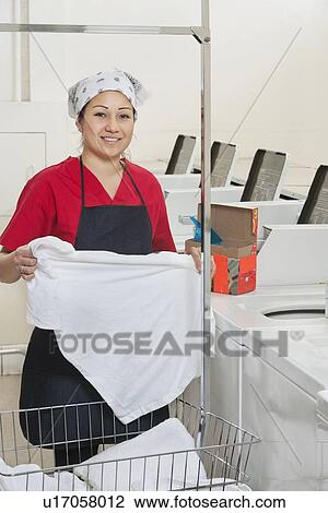 Portrait of a happy woman wearing uniform holding clothes with washing machines in background View Large Photo Image Stock Image - Portrait of a happy woman wearing uniform holding clothes with washing machines in background. Fotosearch