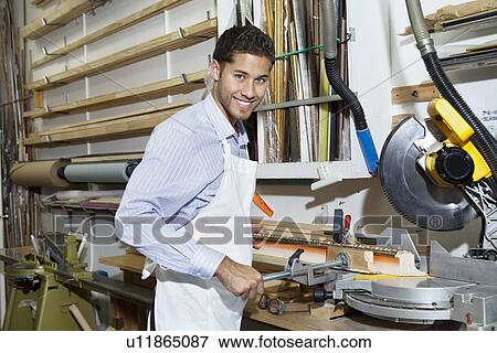 Portrait of a happy young craftsman standing by circular saw machinery View Large Photo Image Stock Photo - Portrait of a happy young craftsman standing by circular saw machinery. Fotosearch