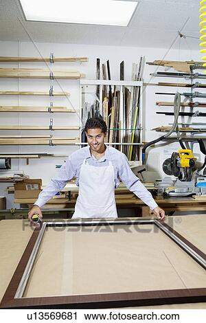Portrait of a happy young employee measuring picture frame View Large Photo Image Stock Image - Portrait of a happy young employee measuring picture frame. Fotosearch