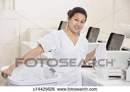 Portrait of a happy young employee standing by washing machines in Laundromat View Large Photo Image Stock Photo - Portrait of a happy young employee standing by washing machines in Laundromat. Fotosearch