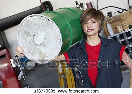 Portrait of a happy young female mechanic carrying oil drum on shoulder in car workshop View Large Photo Image Stock Photography - Portrait of a happy young female mechanic carrying oil drum on shoulder in car workshop. Fotosearch