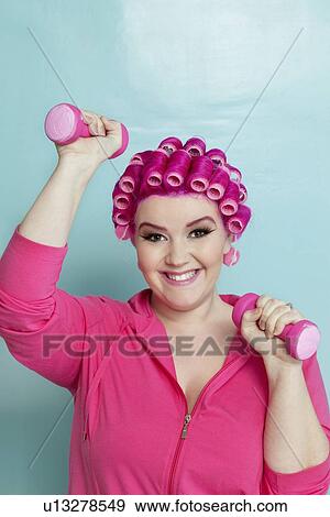 Portrait of a happy young woman lifting weights over colored background View Large Photo Image Stock Photo - Portrait of a happy young woman lifting weights over colored background. Fotosearch