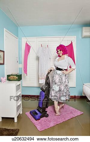 Portrait of a happy young woman vacuuming carpet View Large Photo Image Picture - Portrait of a happy young woman vacuuming carpet. Fotosearch