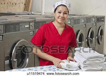 Picture - Portrait of a Hispanic female employee with towel in Laundromat. Fotosearch