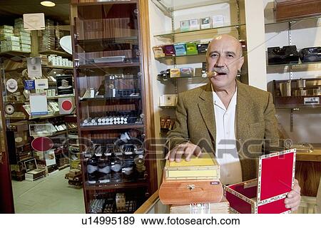 Stock Photo - Portrait of a mature man smoking cigar with display in background. Fotosearch
