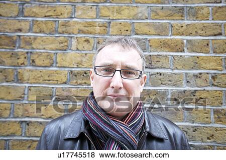 Portrait of a mature man wearing glasses with scarf against wall View Large Photo Image Stock Photo - Portrait of a mature man wearing glasses with scarf against wall. Fotosearch