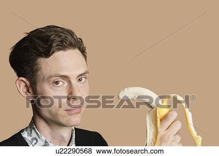 Portrait of a mid adult man holding banana over colored background View Large Photo Image Stock Photo - Portrait of a mid adult man holding banana over colored background. Fotosearch