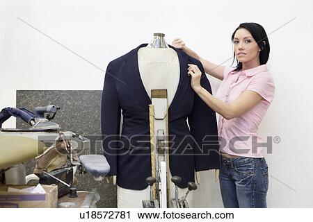 Stock Image - Portrait of a mid adult woman dressing mannequin. Fotosearch