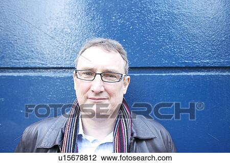 Stock Image - Portrait of a relaxed mature man against blue wall. Fotosearch