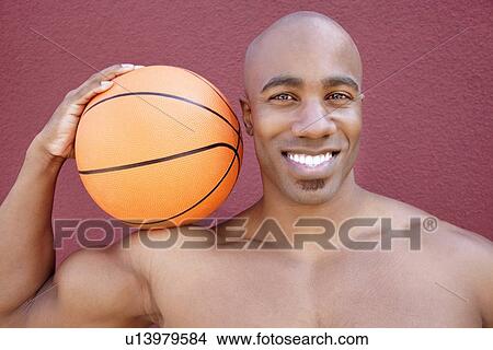Portrait of a young African American man with basketball on shoulder over colored background View Large Photo Image Picture - Portrait of a young African American man with basketball on shoulder over colored background. Fotosearch
