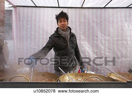 Stock Photo - Portrait of a young Asian man cooking at street food stall. Fotosearch