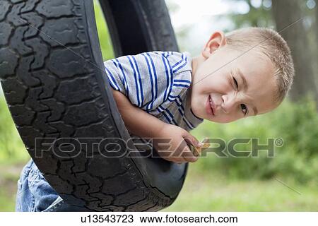Portrait of a young boy winking while swinging on tire View Large Photo Image Stock Image - Portrait of a young boy winking while swinging on tire. Fotosearch
