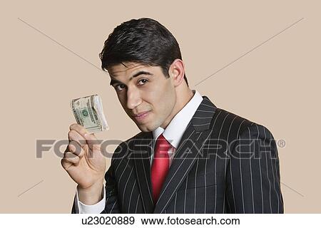 Portrait of a young businessman showing paper money over colored background View Large Photo Image Stock Photo - Portrait of a young businessman showing paper money over colored background. Fotosearch