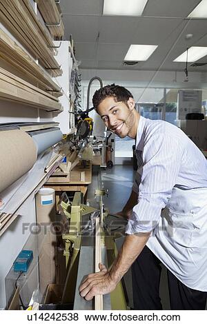 Stock Photo - Portrait of a young employee working on wood. Fotosearch