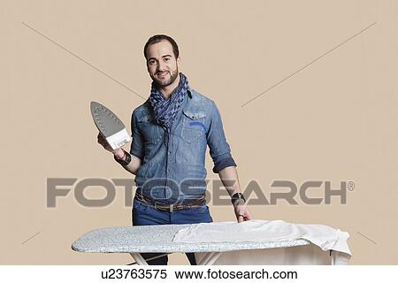 Portrait of a young man holding iron over colored background View Large Photo Image Stock Photography - Portrait of a young man holding iron over colored background. Fotosearch