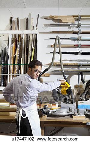 Portrait of a young man looking back while using circular saw in workshop View Large Photo Image Stock Image - Portrait of a young man looking back while using circular saw in workshop. Fotosearch