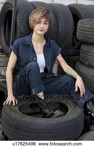 Portrait of a young mechanic sitting on tires in car workshop View Large Photo Image Stock Photo - Portrait of a young mechanic sitting on tires in car workshop. Fotosearch