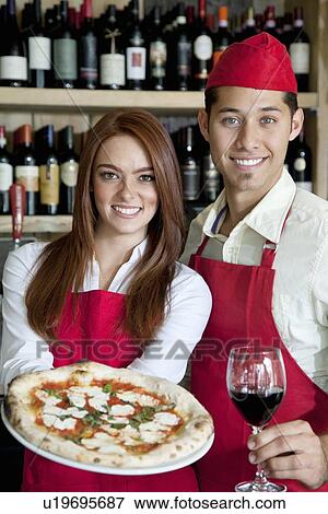 Stock Photo - Portrait of a young wait staff with wine glass and pizza. Fotosearch
