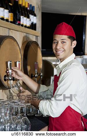 Portrait of a young waiter standing by drinks tap View Large Photo Image Stock Image - Portrait of a young waiter standing by drinks tap. Fotosearch