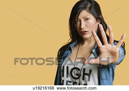 Portrait of a young woman gesturing stop sign over colored background View Large Photo Image Stock Photograph - Portrait of a young woman gesturing stop sign over colored background. Fotosearch
