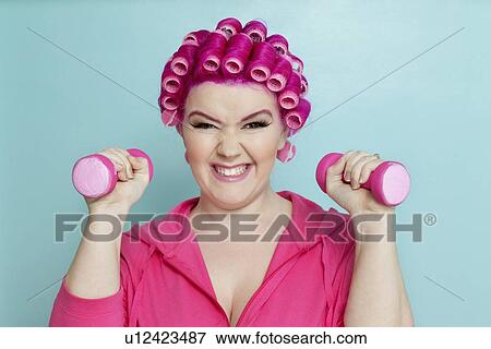 Stock Photo - Portrait of a young woman happy with lifting weights. Fotosearch