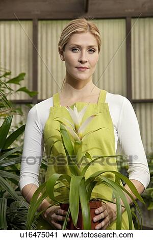 Stock Image - Portrait of a young woman holding potted plant. Fotosearch