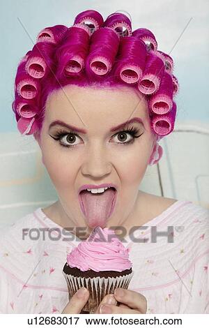 Portrait of a young woman licking cupcake View Large Photo Image Stock Photo - Portrait of a young woman licking cupcake. Fotosearch