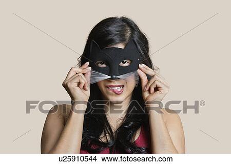 Portrait of a young woman wearing eye mask while biting lip over colored background View Large Photo Image Picture - Portrait of a young woman wearing eye mask while biting lip over colored background. Fotosearch