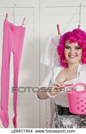 Picture - Portrait of a young woman with clothespin standing in front of clothesline. Fotosearch
