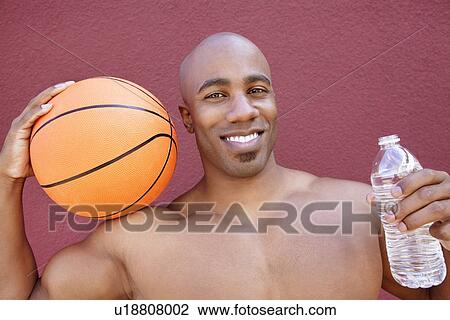 Portrait of an African American athlete with basketball and water bottle over colored background View Large Photo Image Stock Image - Portrait of an African American athlete with basketball and water bottle over colored background. Fotosearch