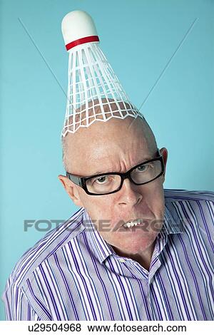 Portrait of angry senior man with shuttlecock on head over colored background View Large Photo Image Stock Photo - Portrait of angry senior man with shuttlecock on head over colored background. Fotosearch