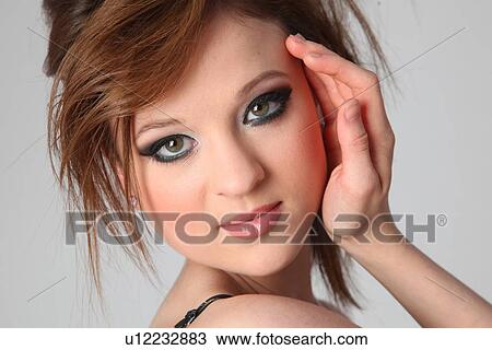 Stock Image - Portrait of beautiful young woman posing over colored background. Fotosearch