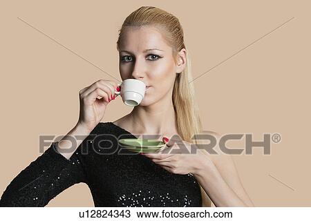 Portrait of beautiful young woman drinking tea over colored background View Large Photo Image Stock Image - Portrait of beautiful young woman drinking tea over colored background. Fotosearch