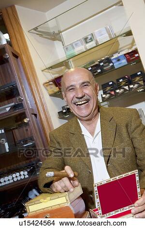 Portrait of cheerful mature man smoking cigar in tobacco store View Large Photo Image Picture - Portrait of cheerful mature man smoking cigar in tobacco store. Fotosearch