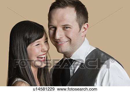 Stock Photo - Portrait of cheerful young couple over colored background. Fotosearch