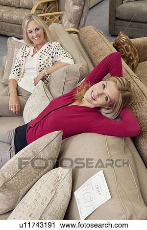 Portrait of daughter relaxing on sofa while mother looking in furniture store View Large Photo Image Stock Image - Portrait of daughter relaxing on sofa while mother looking in furniture store. Fotosearch