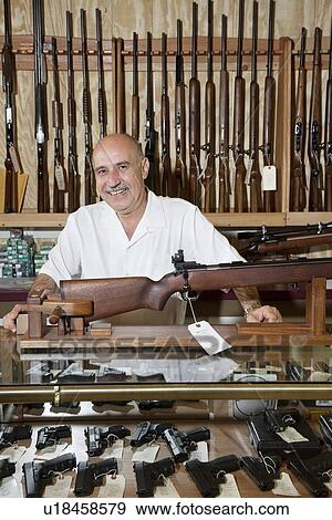 Stock Photo - Portrait of happy mature owner of gun shop. Fotosearch