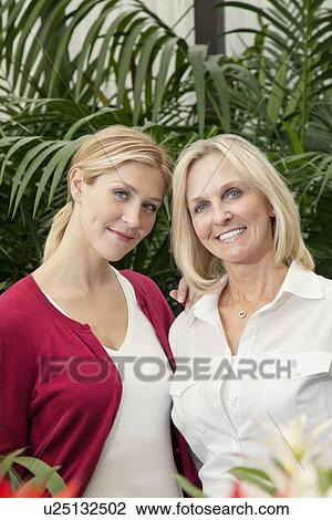 Stock Image - Portrait of happy mother and daughter in greenhouse. Fotosearch