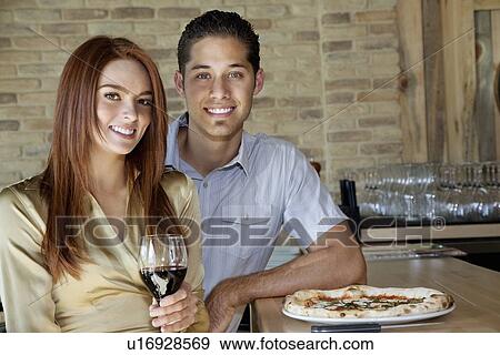 Portrait of happy young couple sitting at counter with pizza and wine View Large Photo Image Stock Photo - Portrait of happy young couple sitting at counter with pizza and wine. Fotosearch