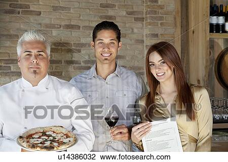 Portrait of mid adult chef holding pizza with young couple View Large Photo Image Stock Image - Portrait of mid adult chef holding pizza with young couple. Fotosearch