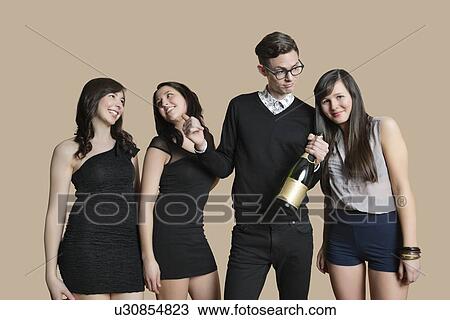 Portrait of mid adult man and young females holding champagne bottle over colored background View Large Photo Image Stock Image - Portrait of mid adult man and young females holding champagne bottle over colored background. Fotosearch
